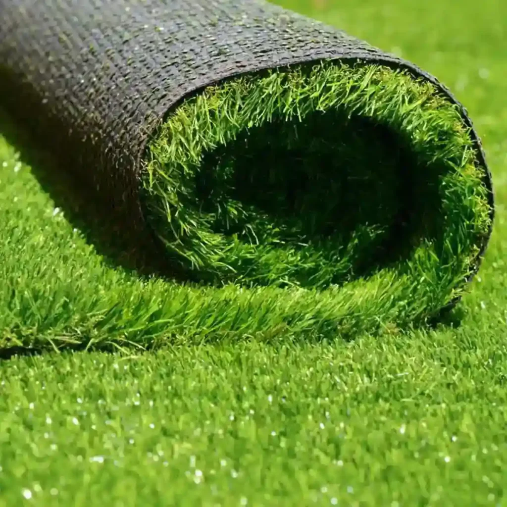 A close-up view of a rolled artificial grass mat placed on a green lawn surface.