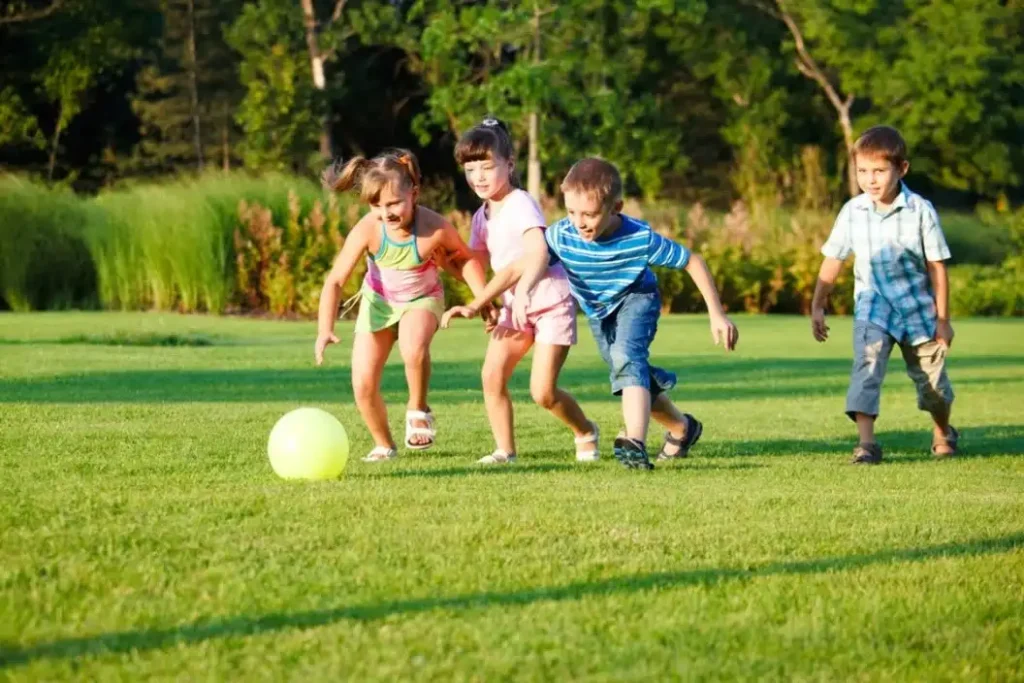 four kids palying football on artificial grass ground