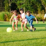 four kids palying football on artificial grass ground
